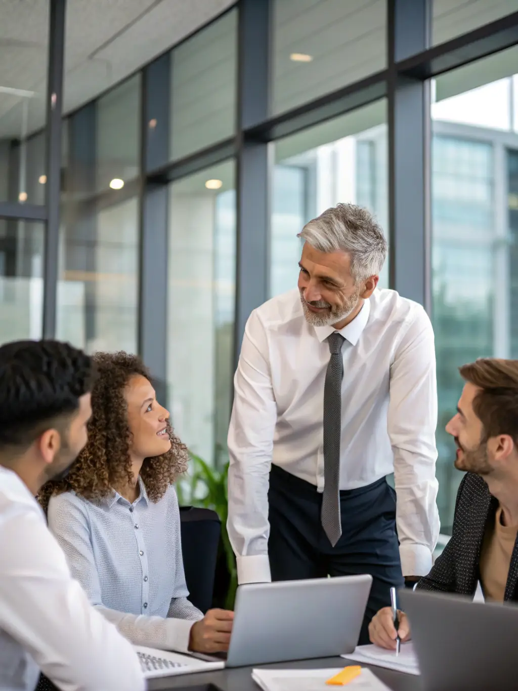 A consultant in a meeting, guiding a team through a strategic planning session, with charts and graphs visible in the background, representing strategic planning.